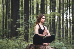 Young girl practices yoga in the forest, the concept of enjoying privacy and concentration, sunlight
